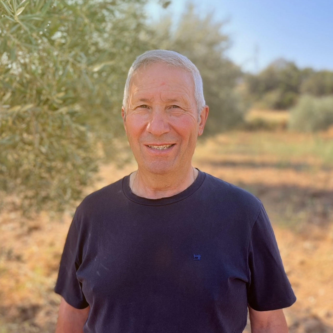 Ein Portraitfoto von Manuel, aufgenommen vor einem Olivenbaum in Portugal.